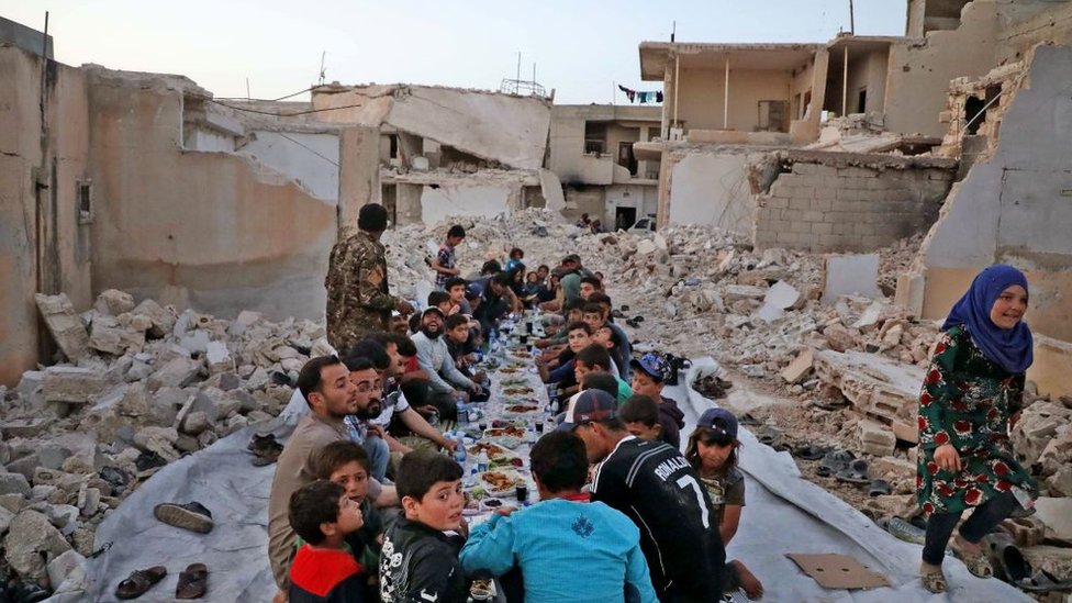 A group of minors eat in a ruined area in Syria 