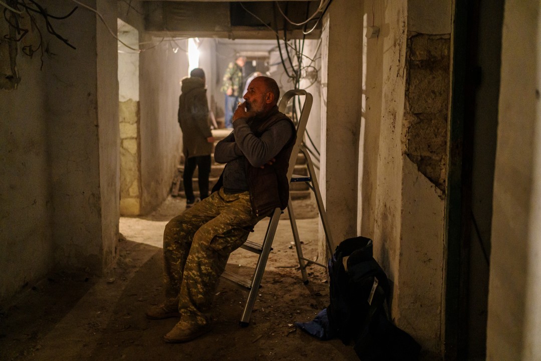  A man takes a cigarette break in an underground bunker as bombing sirens wail.