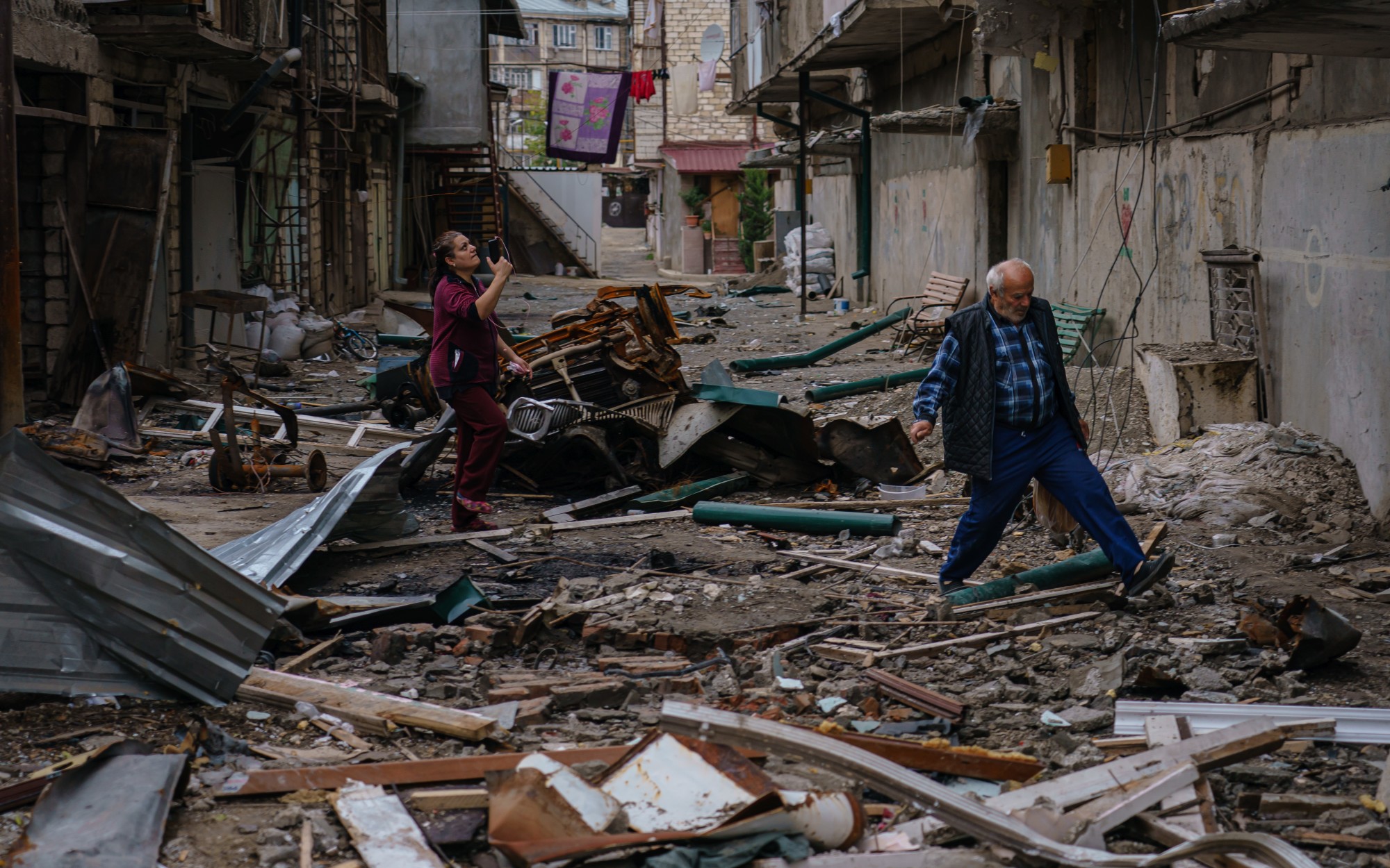 Local residents navigate a debris field outside a destroyed residential area in Stepanakert, Nagorno-Karabakh. 