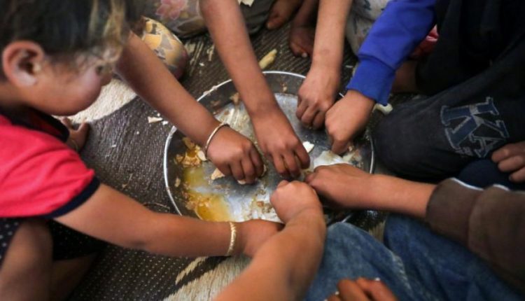 أطفال يتناولون الطعام في مخيم أطمة الحدودي مع تركيا (رويترز)